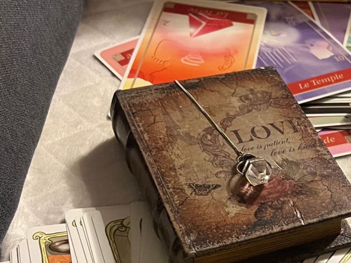 Les cartes de Manon et son pendule en cristal posé sur une boîte ancienne